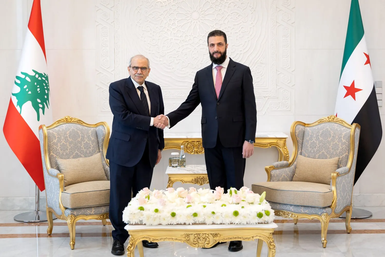 Lebanese Prime Minister Nawaf Salam shaking hands with Syrian President Ahmed al-Sharaa at the People's Palace in Damascus, flanked by both delegations.