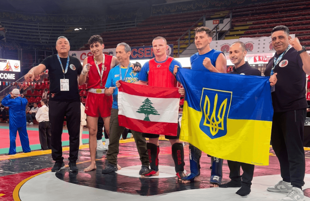 Jad Daoud stands on the competition mat holding the Lebanese flag after winning gold at the Italian International Wushu Kung Fu Championship in Perugia
