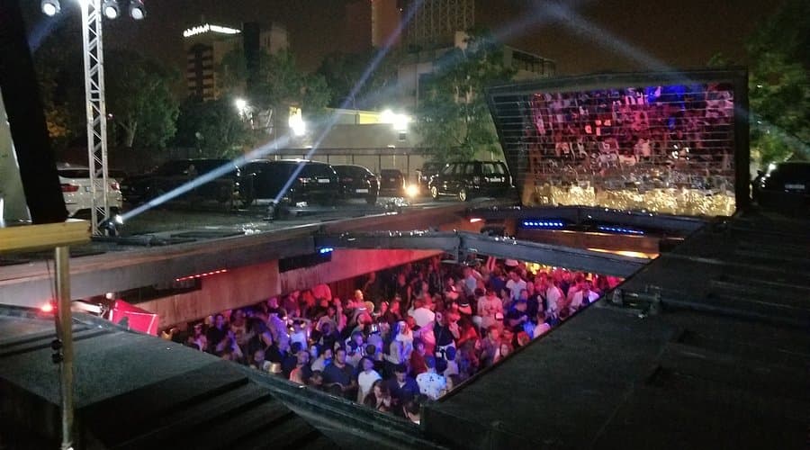 The retractable roof of B018 nightclub sliding open at night in Beirut's Karantina district, with the crowd visible in the sunken hall below