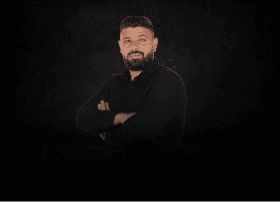 Elias Ziadeh, founder and CEO of Zero to Sixty, standing with his arms crossed in a black shirt against a dark studio background.