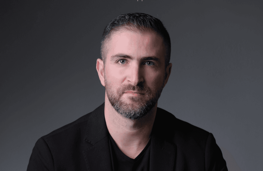 Noel Moukheiber, CEO of Monty Finance S.A.L., in a blue blazer and white shirt, seated against a dark grey background