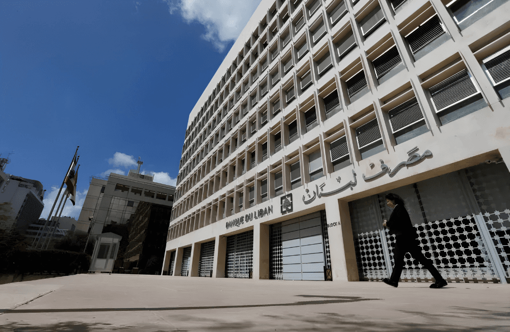 Exterior of the Banque du Liban headquarters in Beirut, with the central bank's Arabic and French signage above the entrance and a man walking past on the empty forecourt