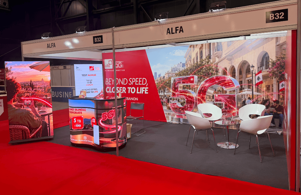 Alfa's red and white booth B32 at Project Lebanon, with a large 5G graphic over a Beirut street scene, the "Beyond Speed, Closer to Life" slogan, white lounge chairs and a 5G promo counter