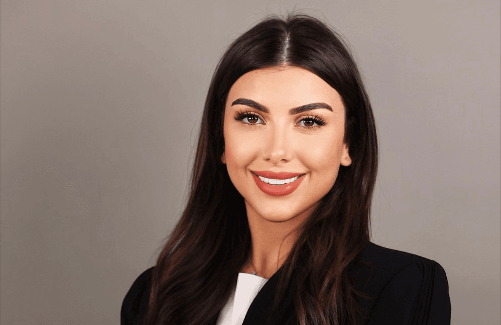 Celine Malian, Senior Consultant at RYZE Advisory & Partners, smiling in a professional portrait with a black blazer against a grey background